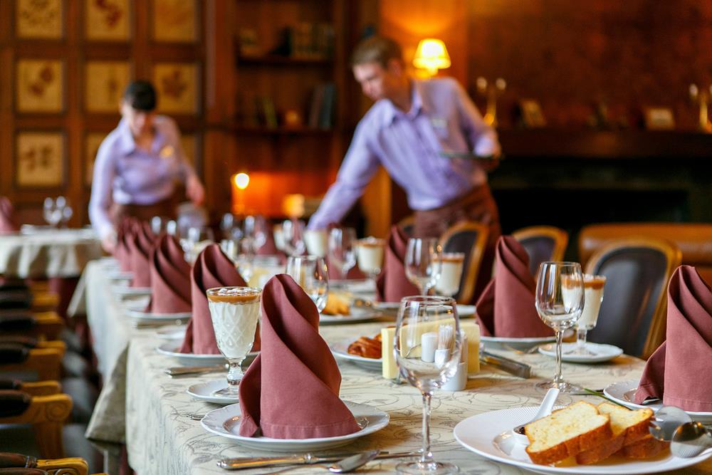 Long table laid for a formal function with waiters in the background