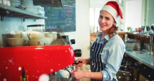 Temporary female barista wearing a Santa hat, working at Christmas