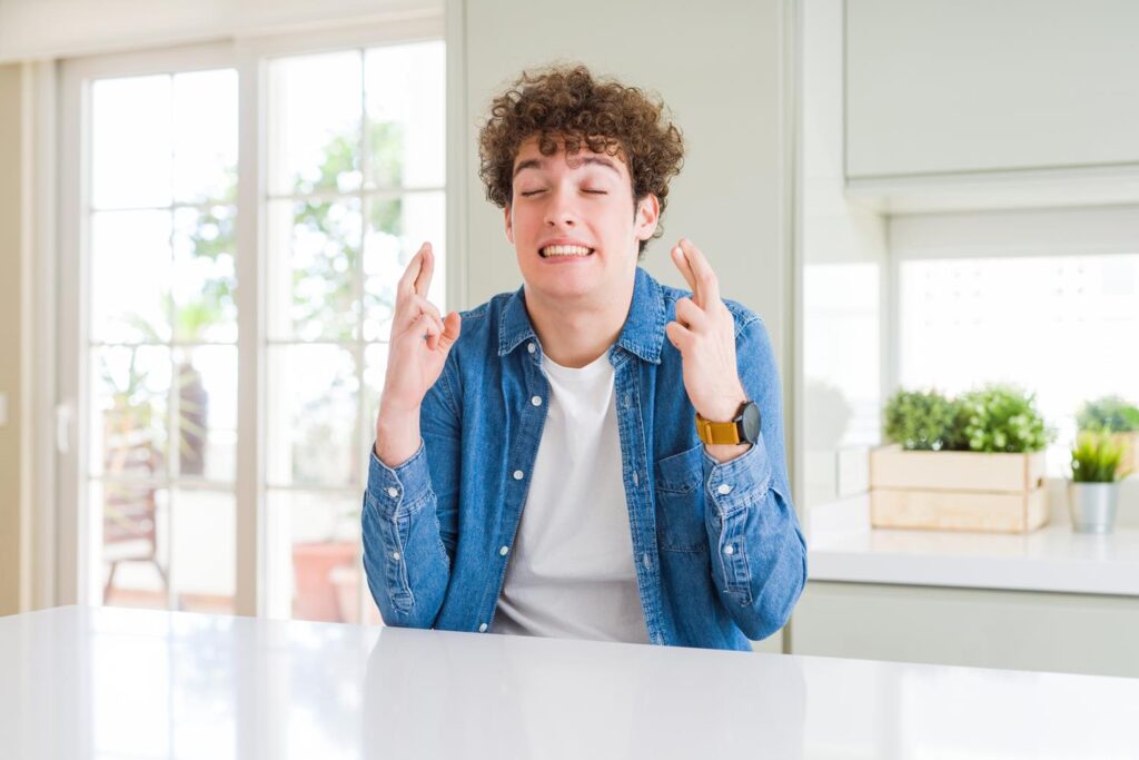 Young man crossing his fingers as he waits to find out if he's got a job