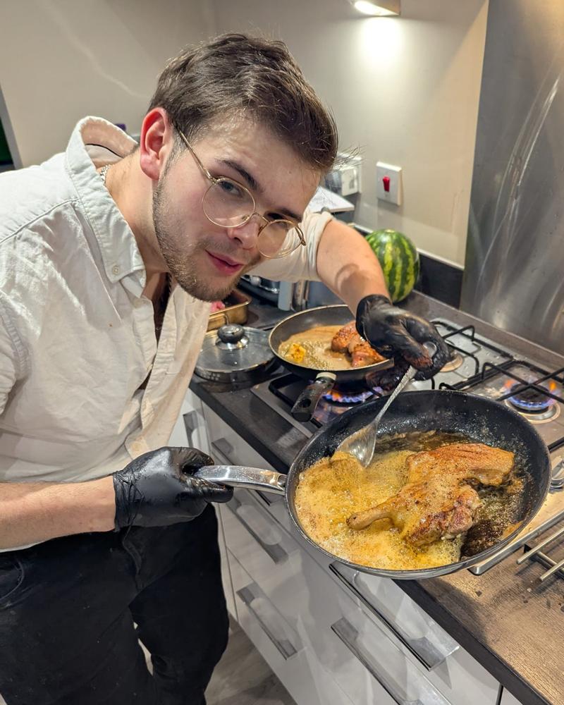 A private chef basting a chicken in a frying pan with a mustard sauce